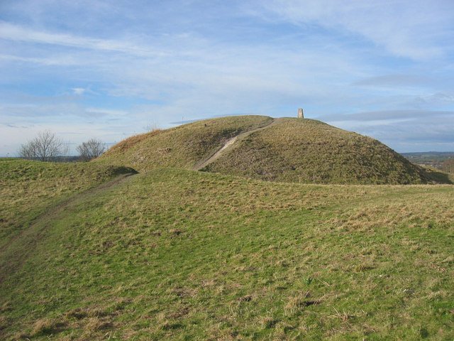 Totternhoe Castle: A large, grassy mound with a winding dirt path and a small stone structure on the summit, which are the remains of Totternhoe Castle.